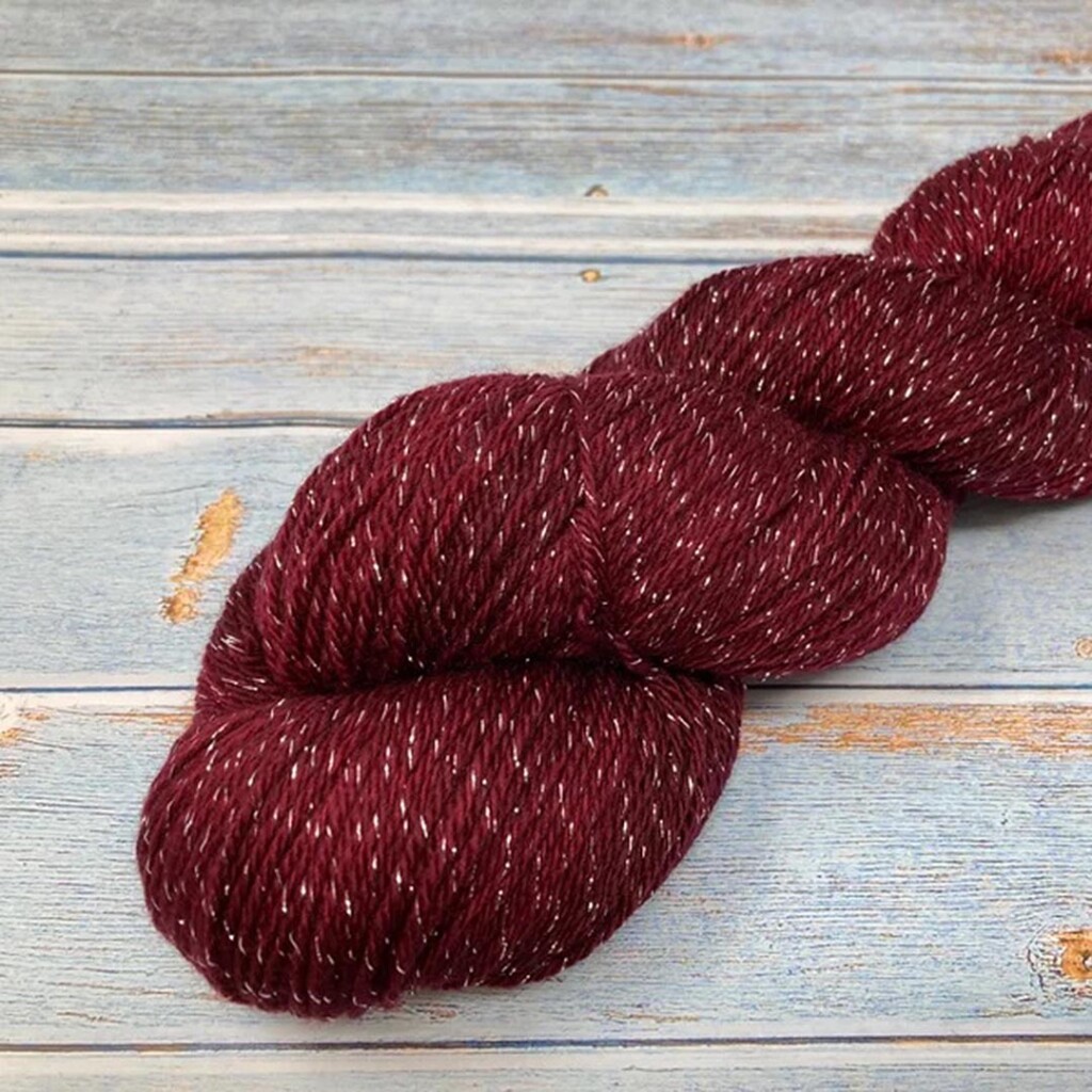 A twisted hank of Leading Men Fiber Arts Sparkle Sock in a deep red shade with shiny silver flecks.