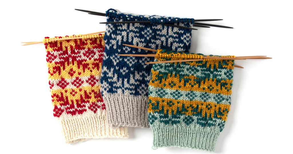 Three colorwork socks are shown in the mid-process of being knit. They're being worked from the cuff down in high contrast colors.